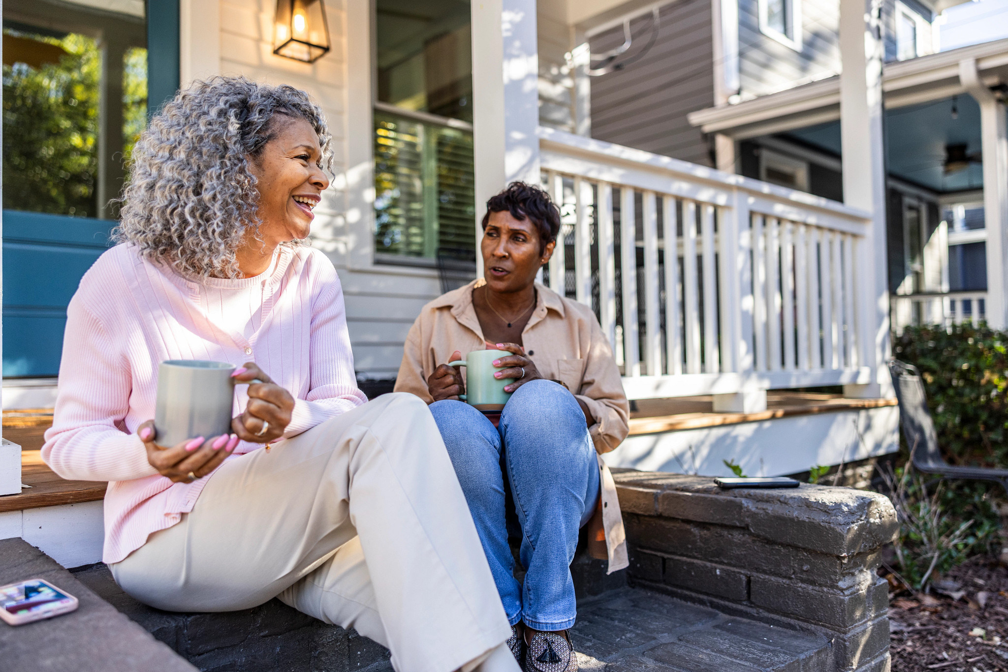 Senior women having coffee on front porch of suburban home