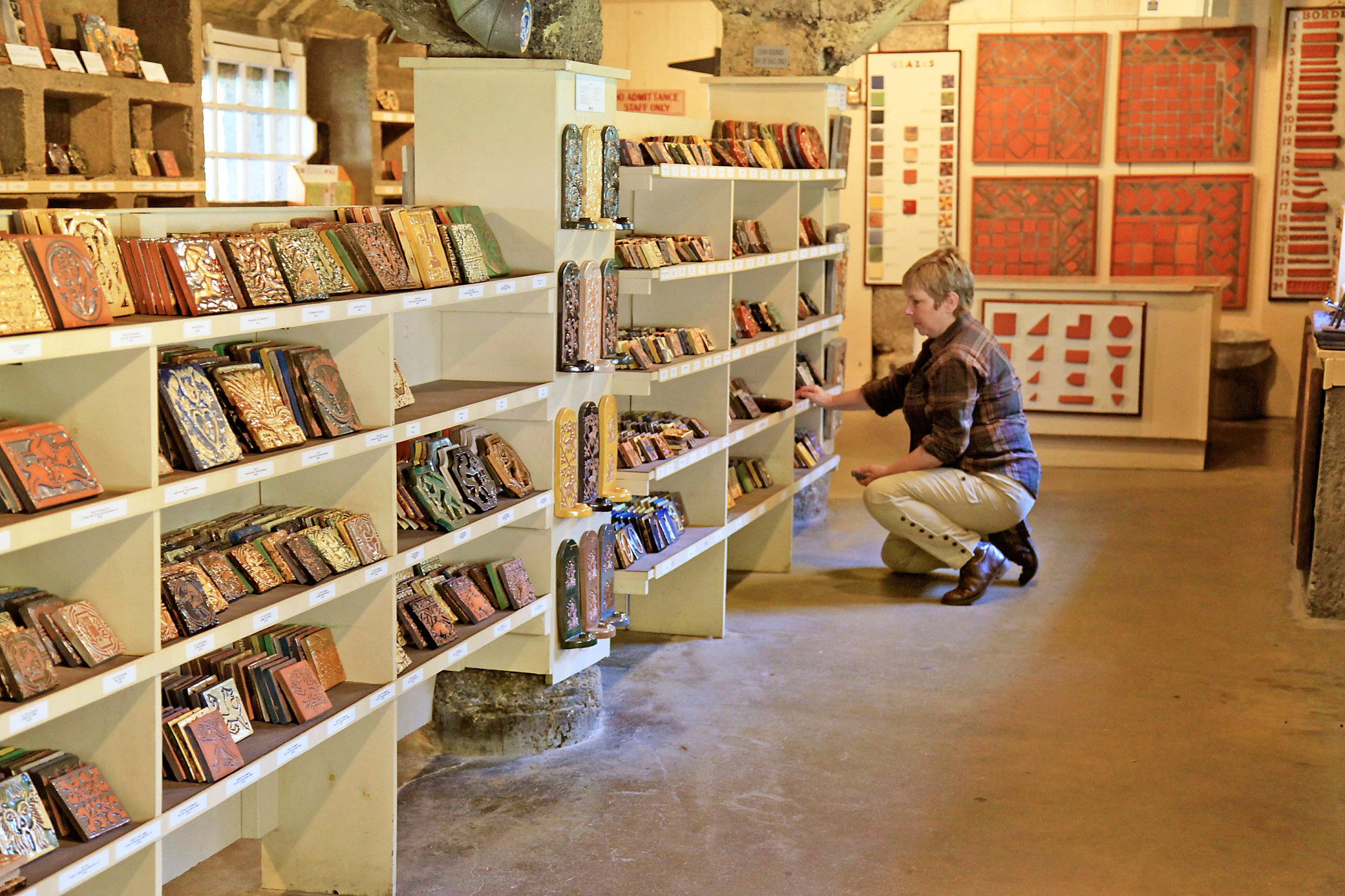 a woman looks at pottery on shelves