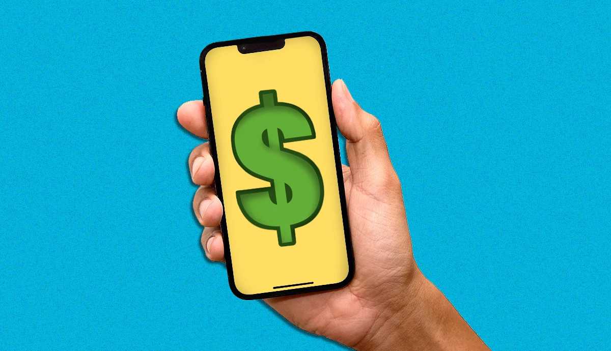 Hand holding a smartphone displaying a large dollar sign on a yellow screen.