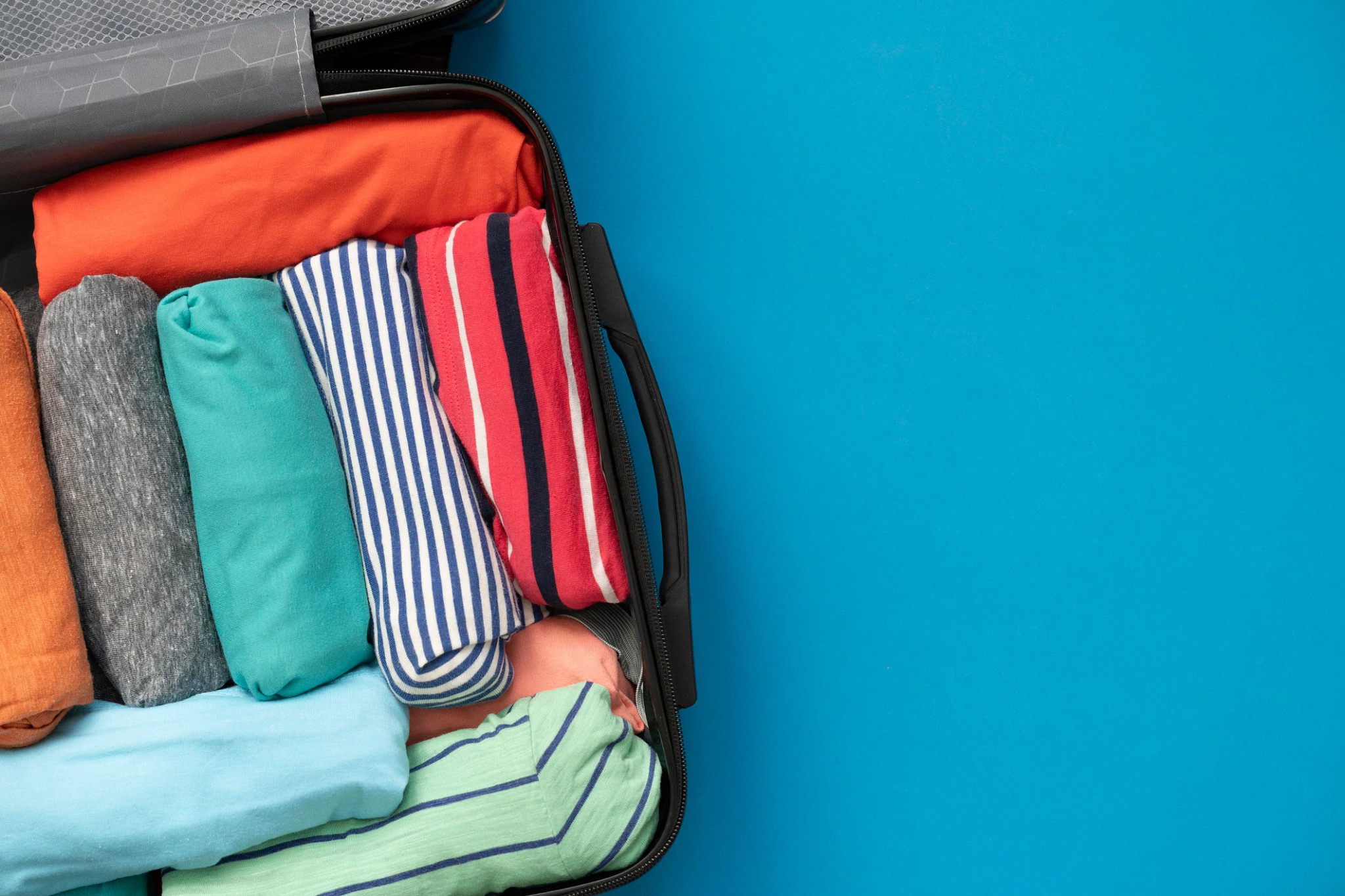 an open suitcase filled with rolled clothes