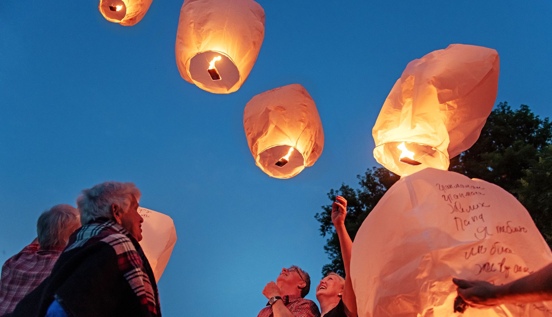 How to plan a memorial service friends smile as they launch paper lanterns into the sky at dusk