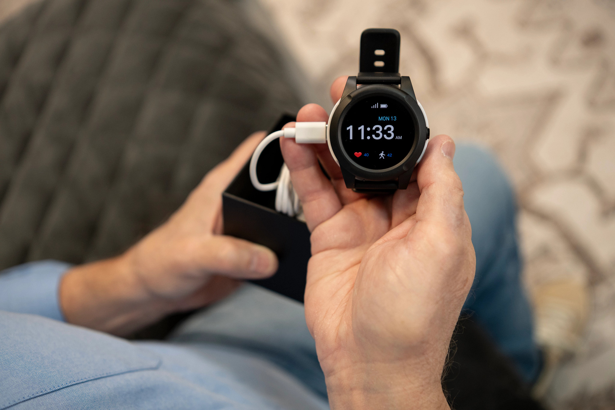 A man holding the Lifefone Safe Watch Active while it’s plugged into the charger.