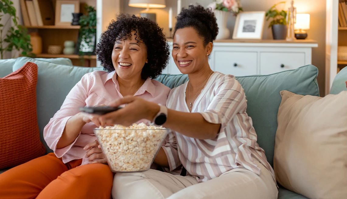 Woman and her adult daughter watching a movie from the Kanopy Library Streaming App on their couch at home