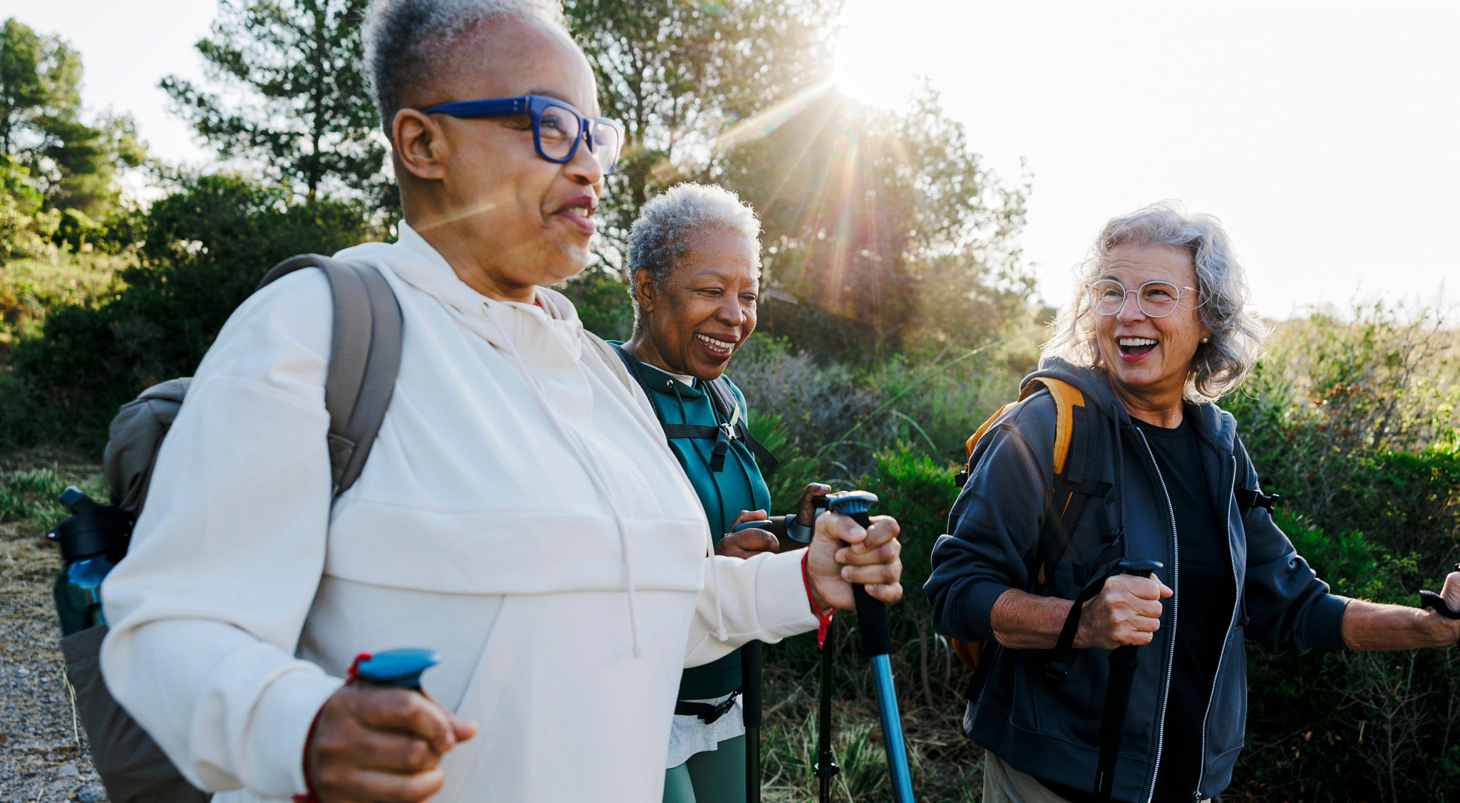 Three women walking together with hiking poles on a sunny day