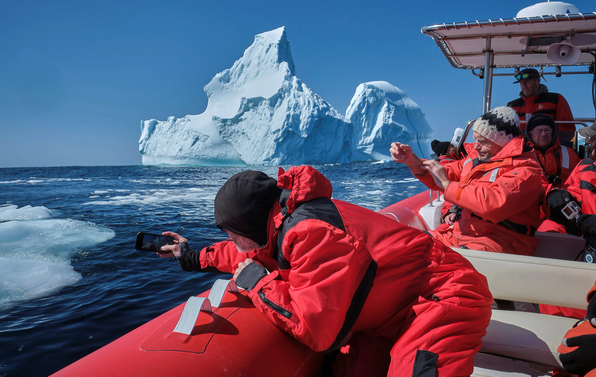 people on a boat taking pictures of icebergs