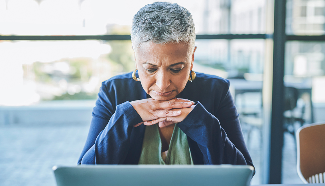 Menopause, brain fog and the workplace may all have a connection A woman with her chin on her hands looking at her laptop in an office