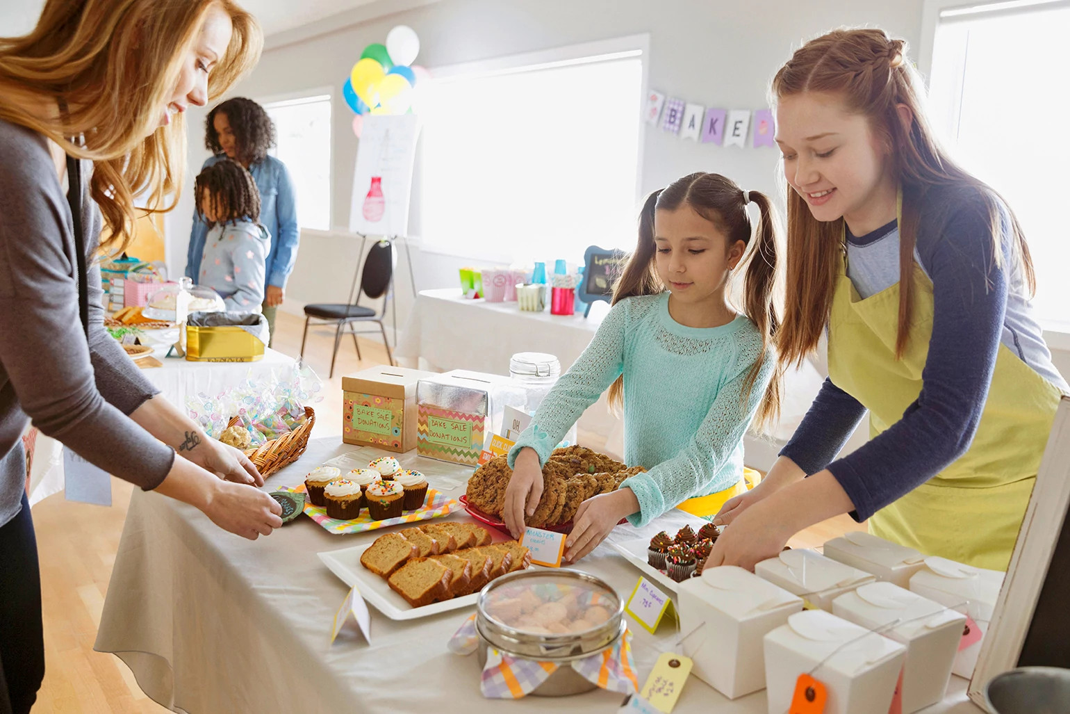 Mom and girls setting up for a bake sale