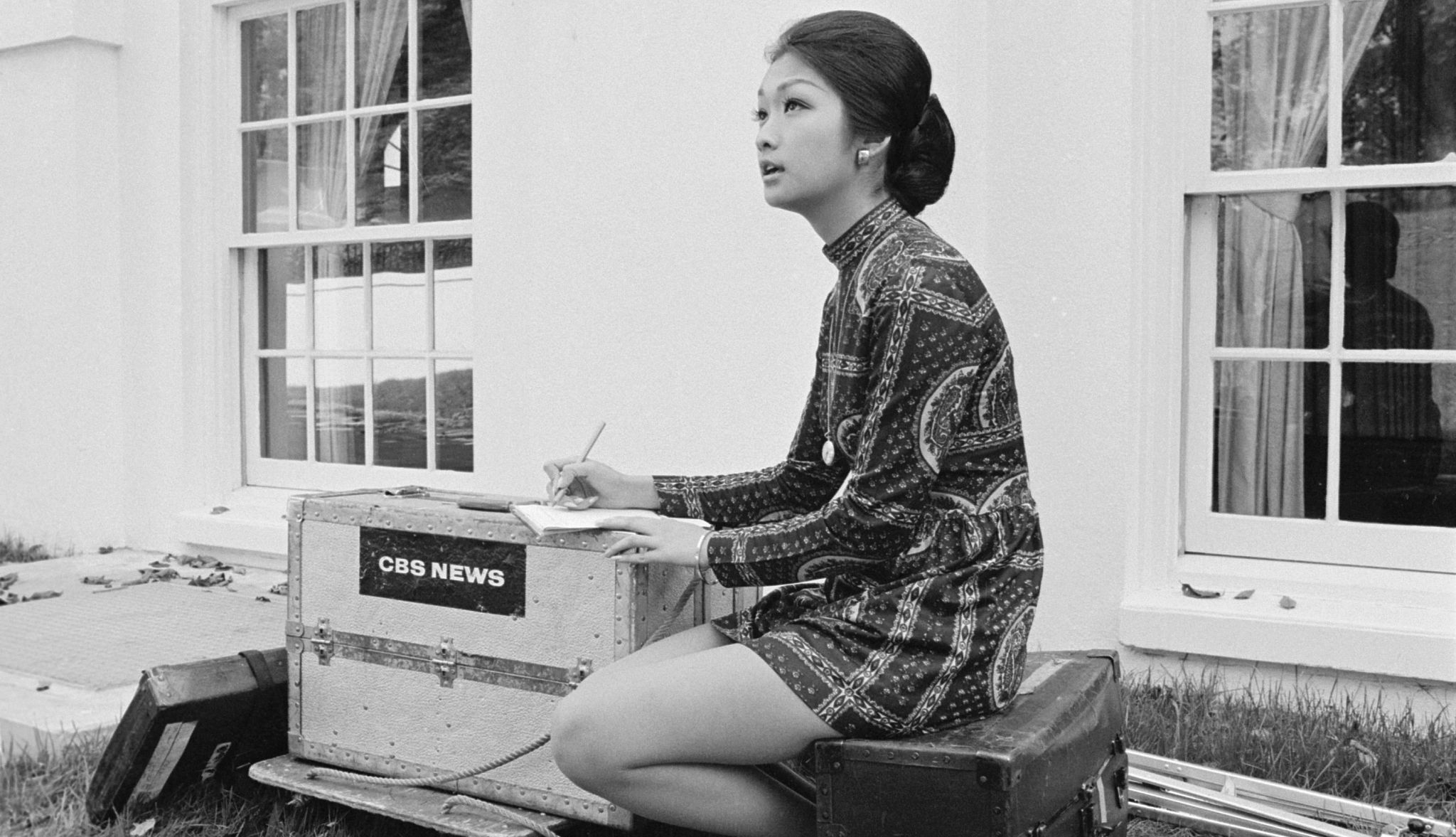 Connie Chung working for CBS News Connie Chung sitting, writing in notebook; notebook is on case that says C B S news