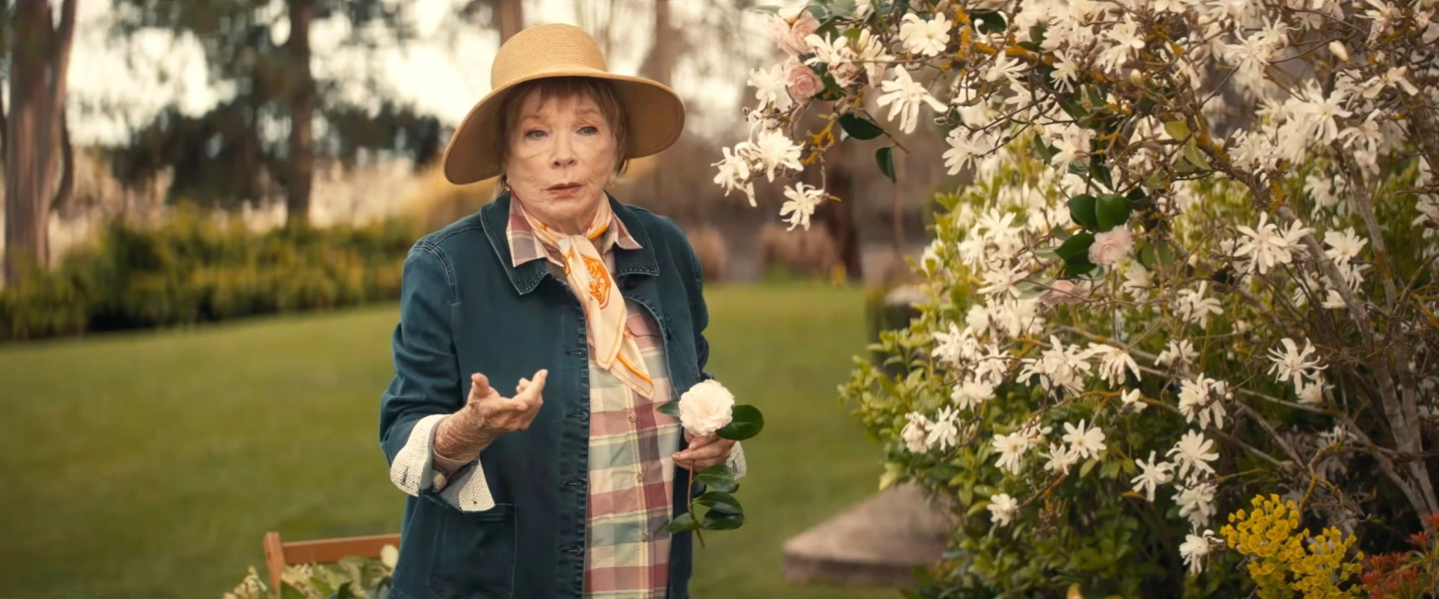 Shirley MacLaine standing in a garden in a scene from American Dreamer