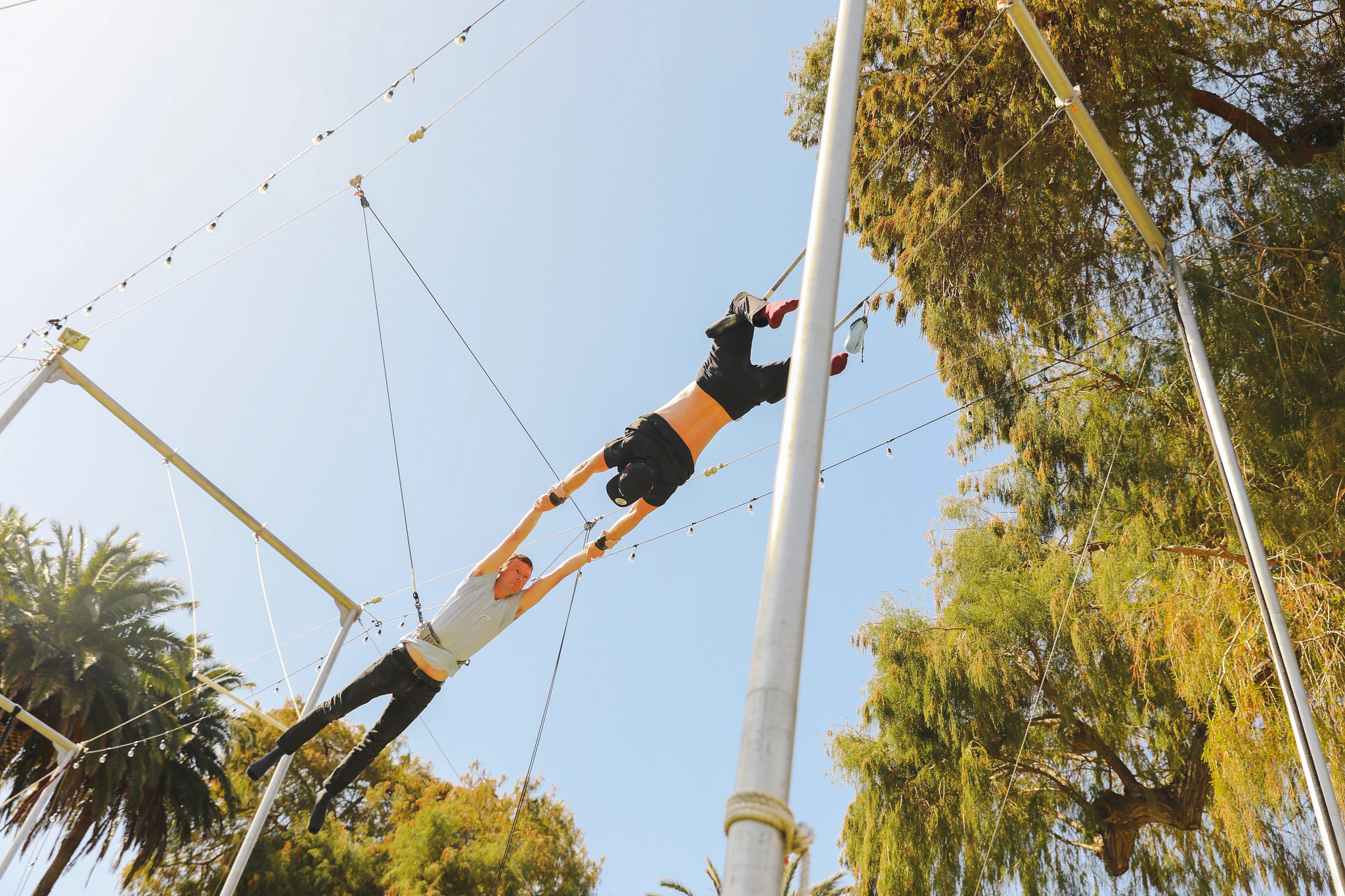 two people performing a flying trapeze maneuver