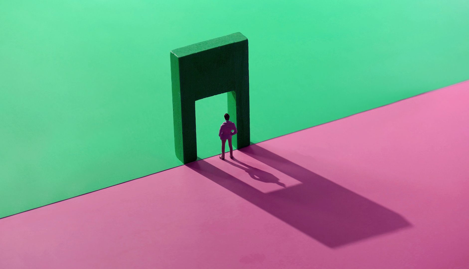 a figure stands in a doorway, with a split pink and green background