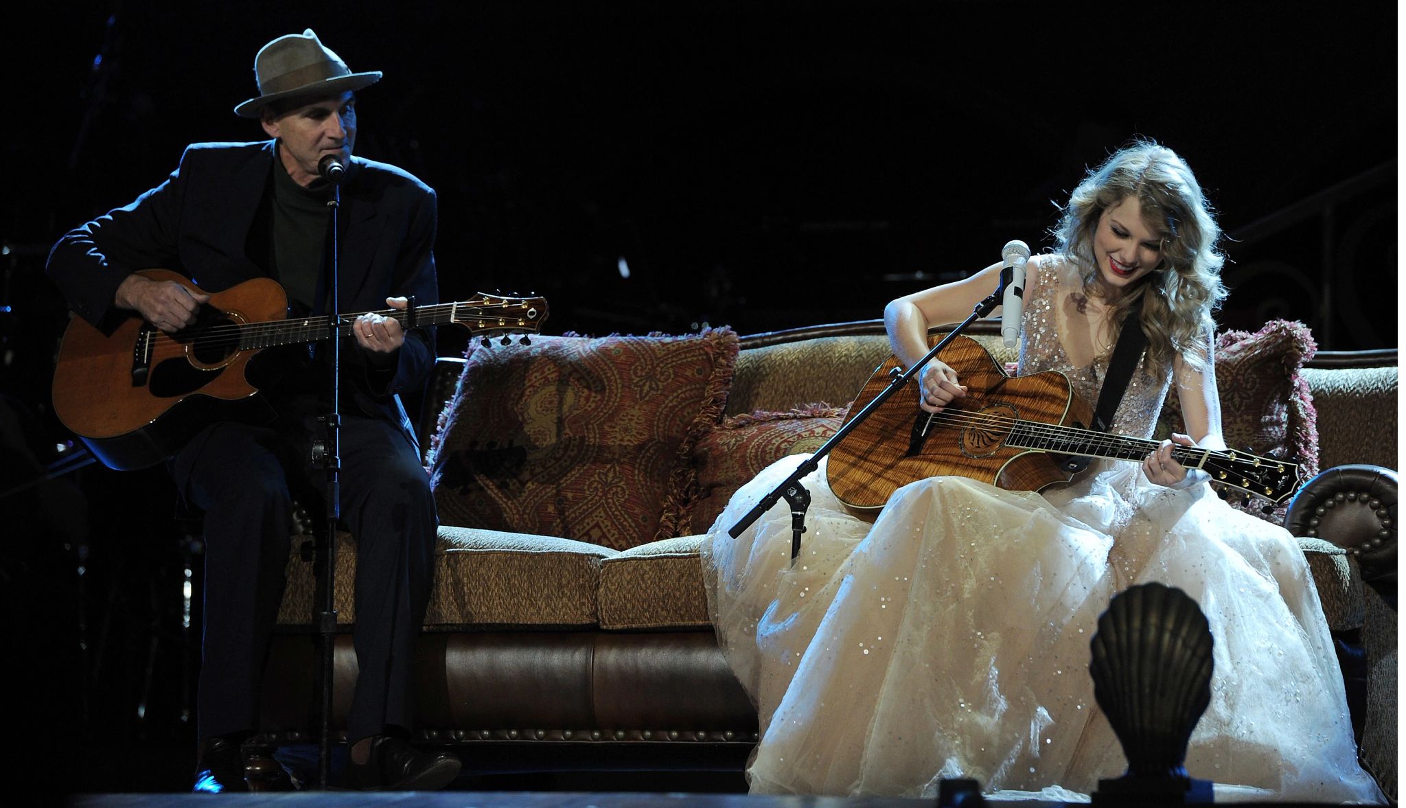 James Taylor and Taylor Swift sitting on couch playing guitar; microphone in front of each of them