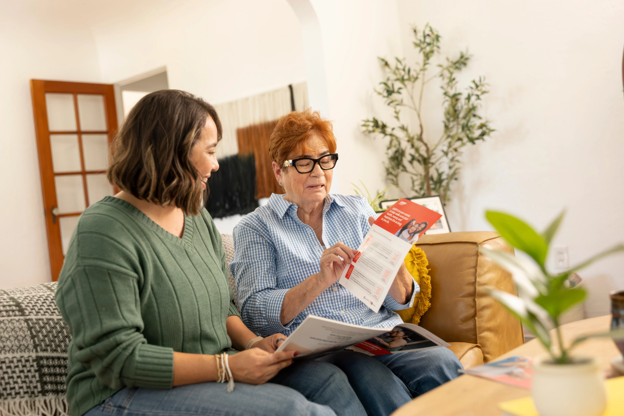 Two people reviewing an informational brochure together at home. Pictured in photo: Luisa Ayala, Carmen Gloria CREDIT: Photograph by Bill Zilman for AARP.