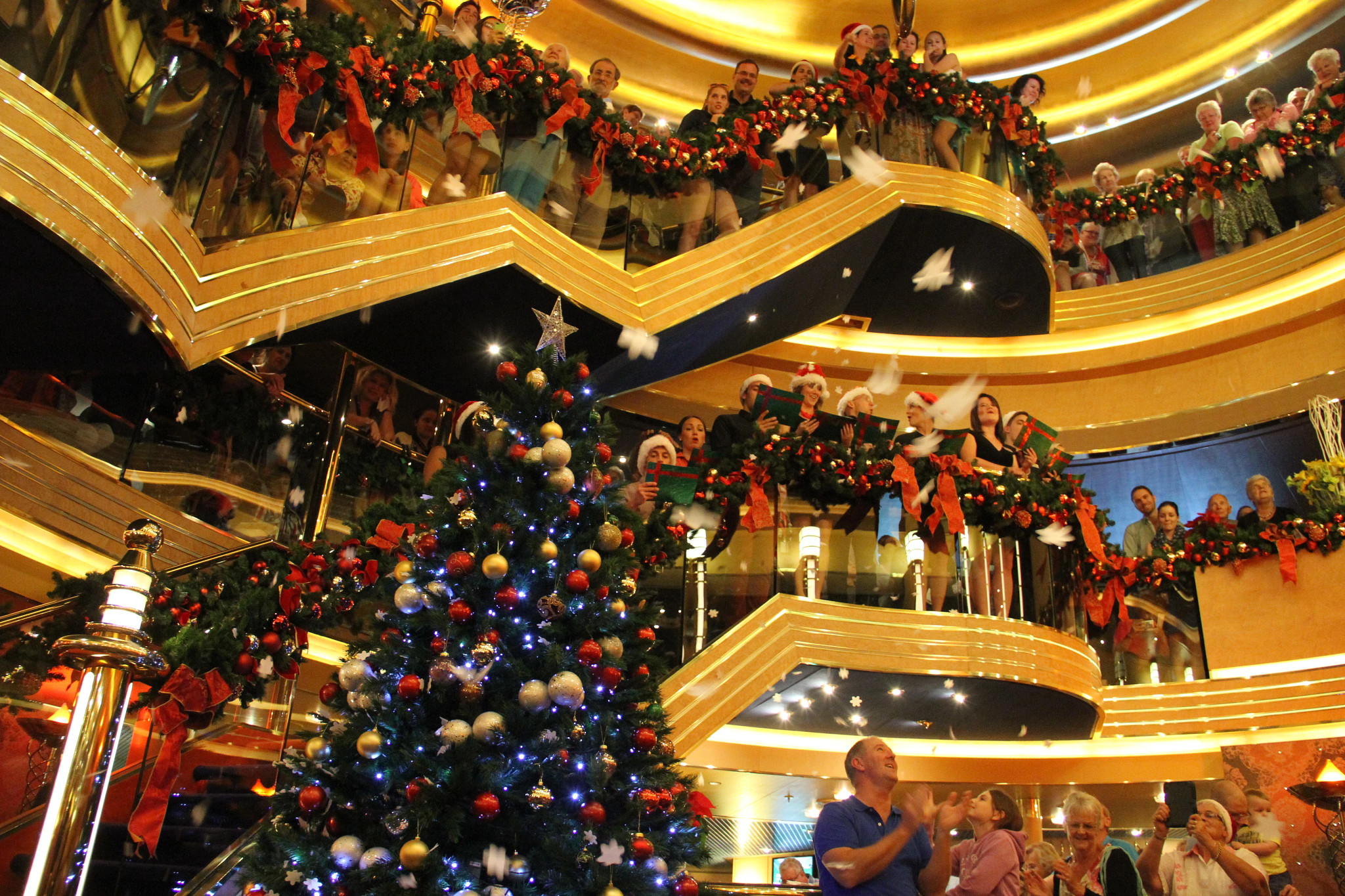 carolers and onlookers line stairs decorated for the holidays