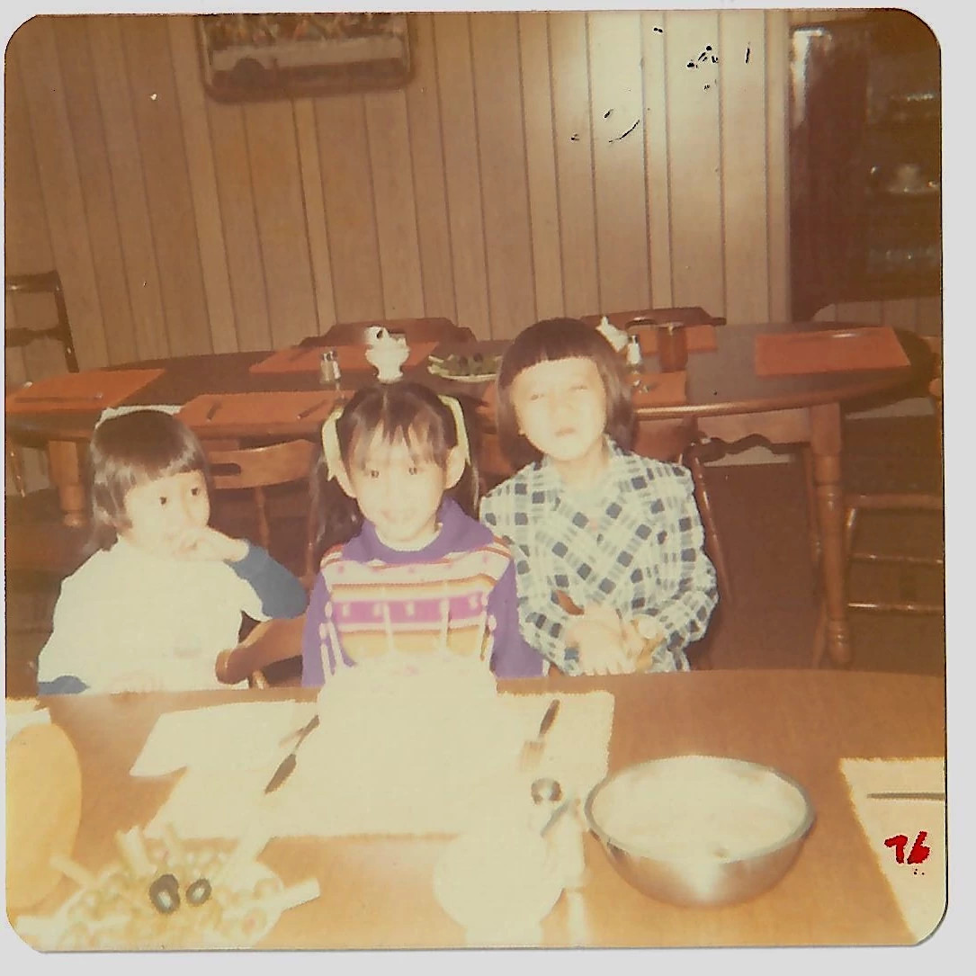 an old photo of three children sitting at a table with a birthday cake