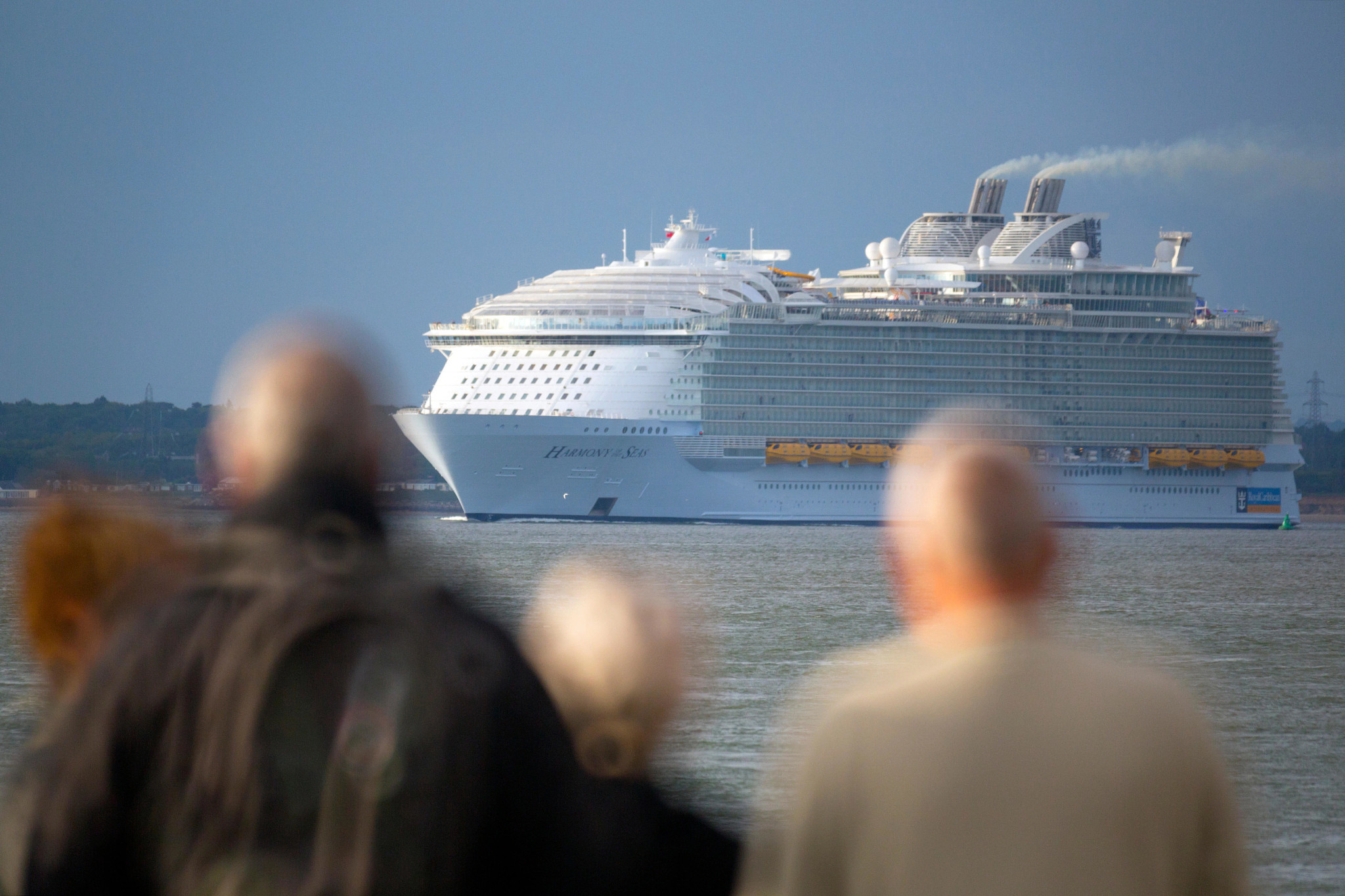 cruise passengers look at cruise ship in the distance