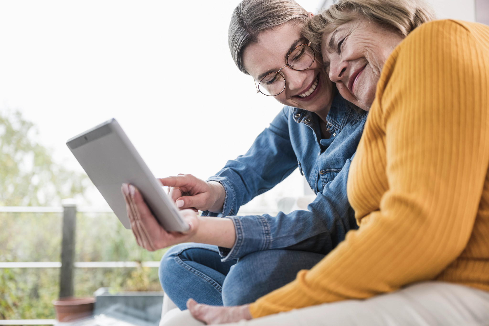 Smiling caregiver using tablet PC with senior woman at home