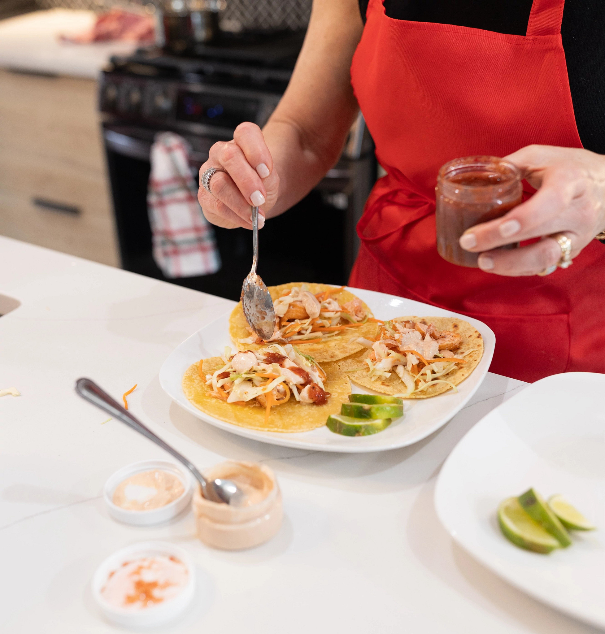 A woman adding sauce to the Sunbasket tacos she prepared.