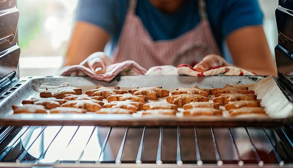 Baking can be a great way to unwind when you have some free time A person taking cookies out of the oven