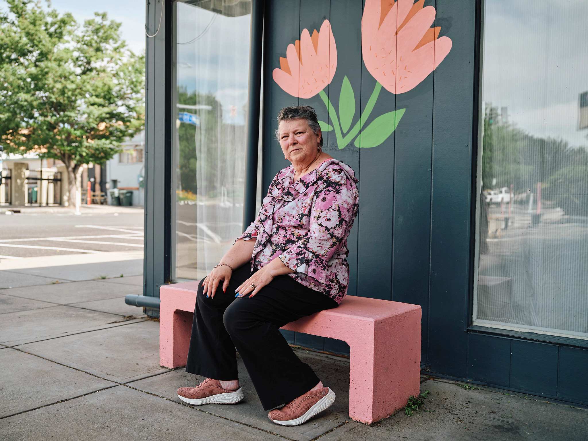 Roberta Burton sentada en un banco rosado en la calle