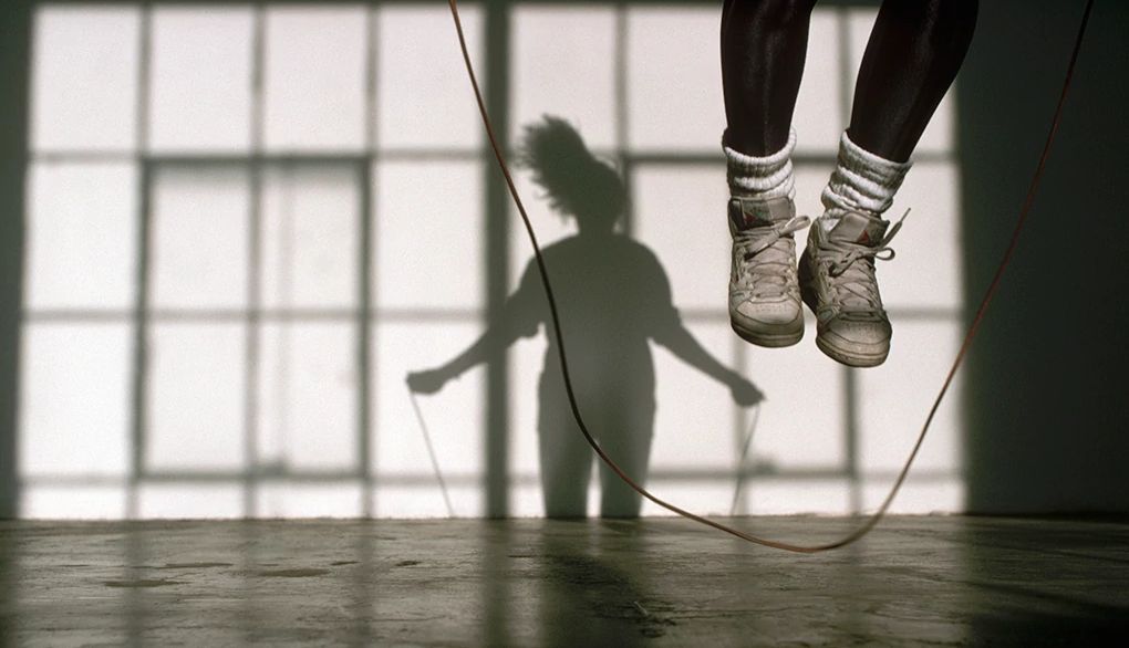 Jumping rope is a fun cardiovascular exercise to help your heart and brain A woman jumping rope casting a shadow on the wall behind her