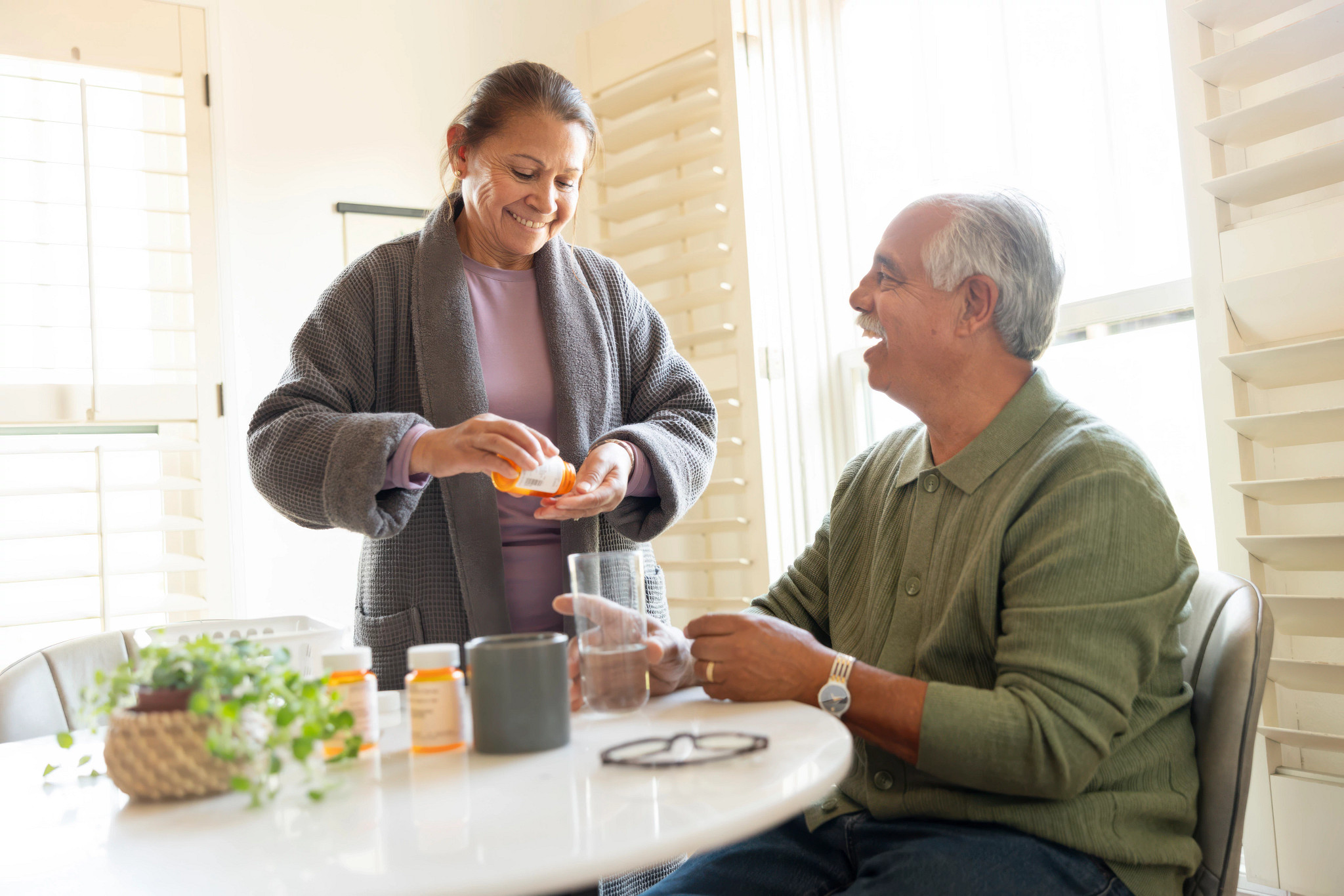 Person dispensing prescription medication for another adult at a table. Pictured in photo: Alicia Lopez, Enrique Lopez  CREDIT: Photograph by Bill Zilman for AARP.