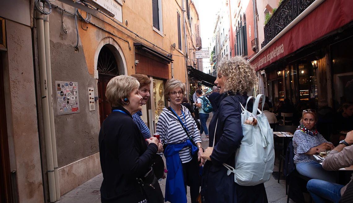 A group of tourists standing on a European street in front of a cafe