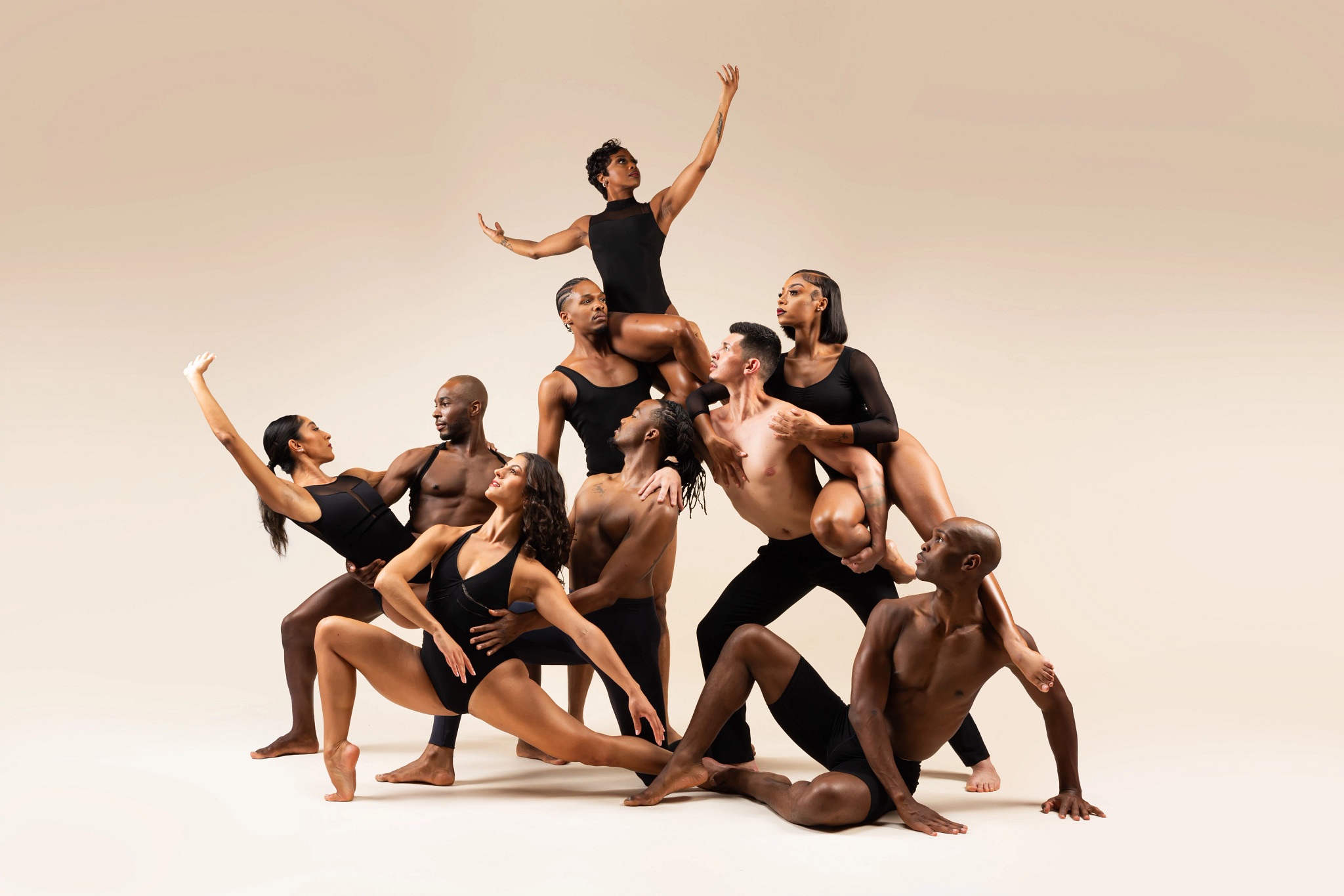An ensemble of dancers arranged in a sculptural formation during a professional dance company photo shoot.