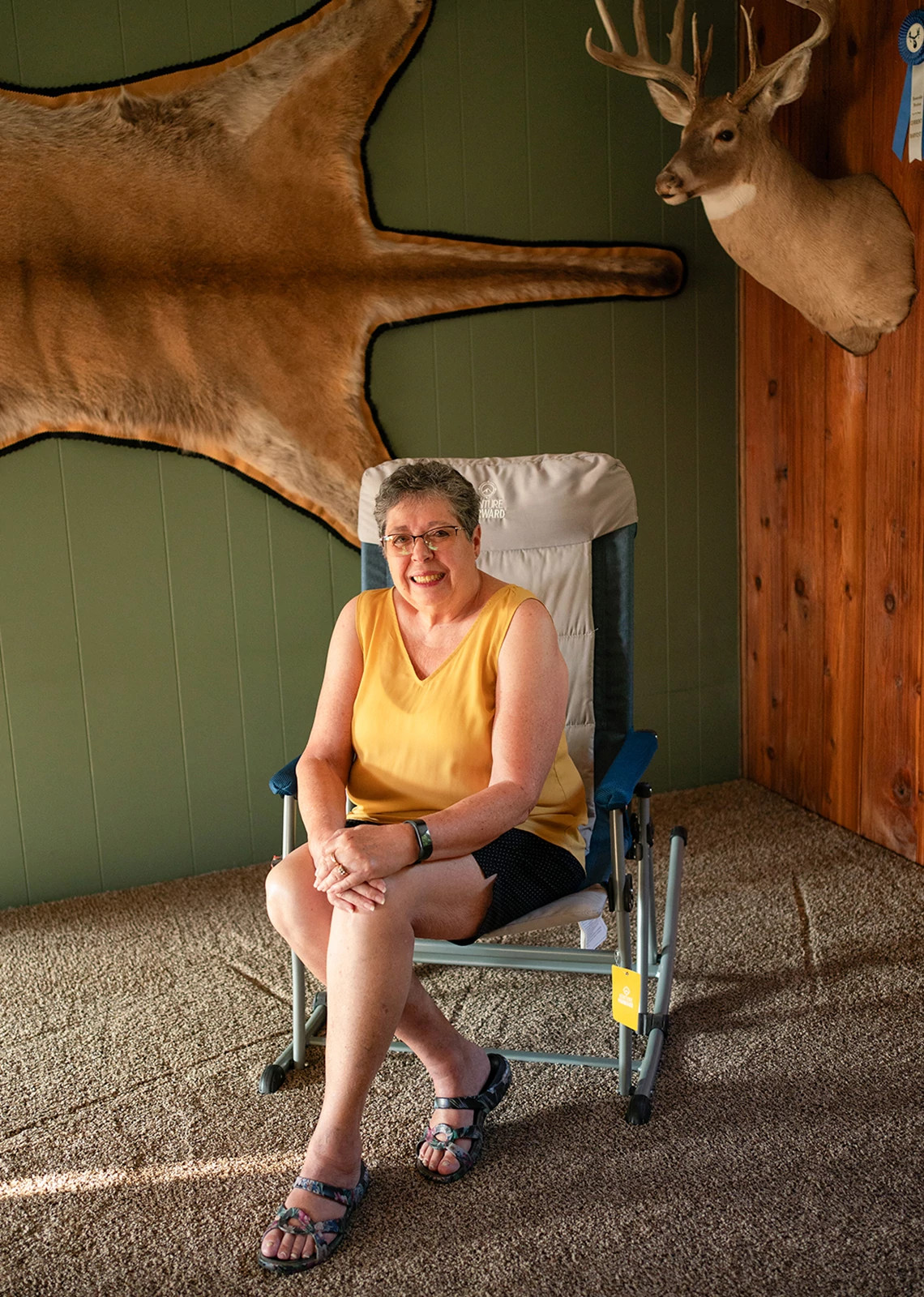 Karen Long, quien lleva una camiseta amarilla sin mangas y pantalones cortos oscuros, aparece sentada en una silla