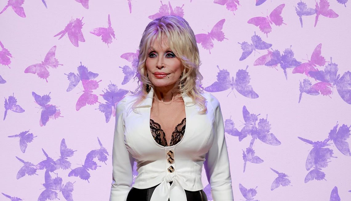 Dolly Parton Says She's Struggling to Write Music dolly parton wearing a white jacket in front of a purple butterfly pattern background