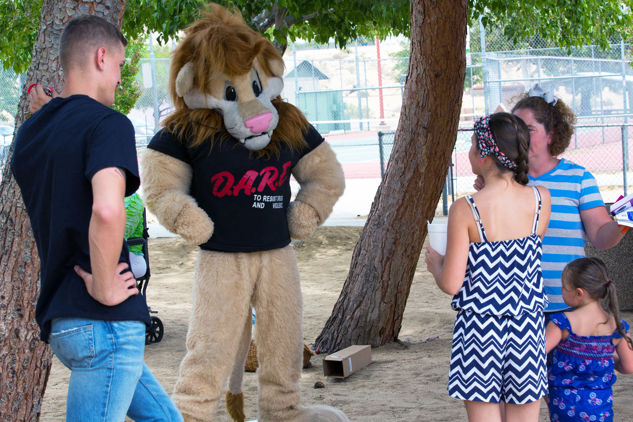 Daren the Lion is shown near a playground talking with parents and kids