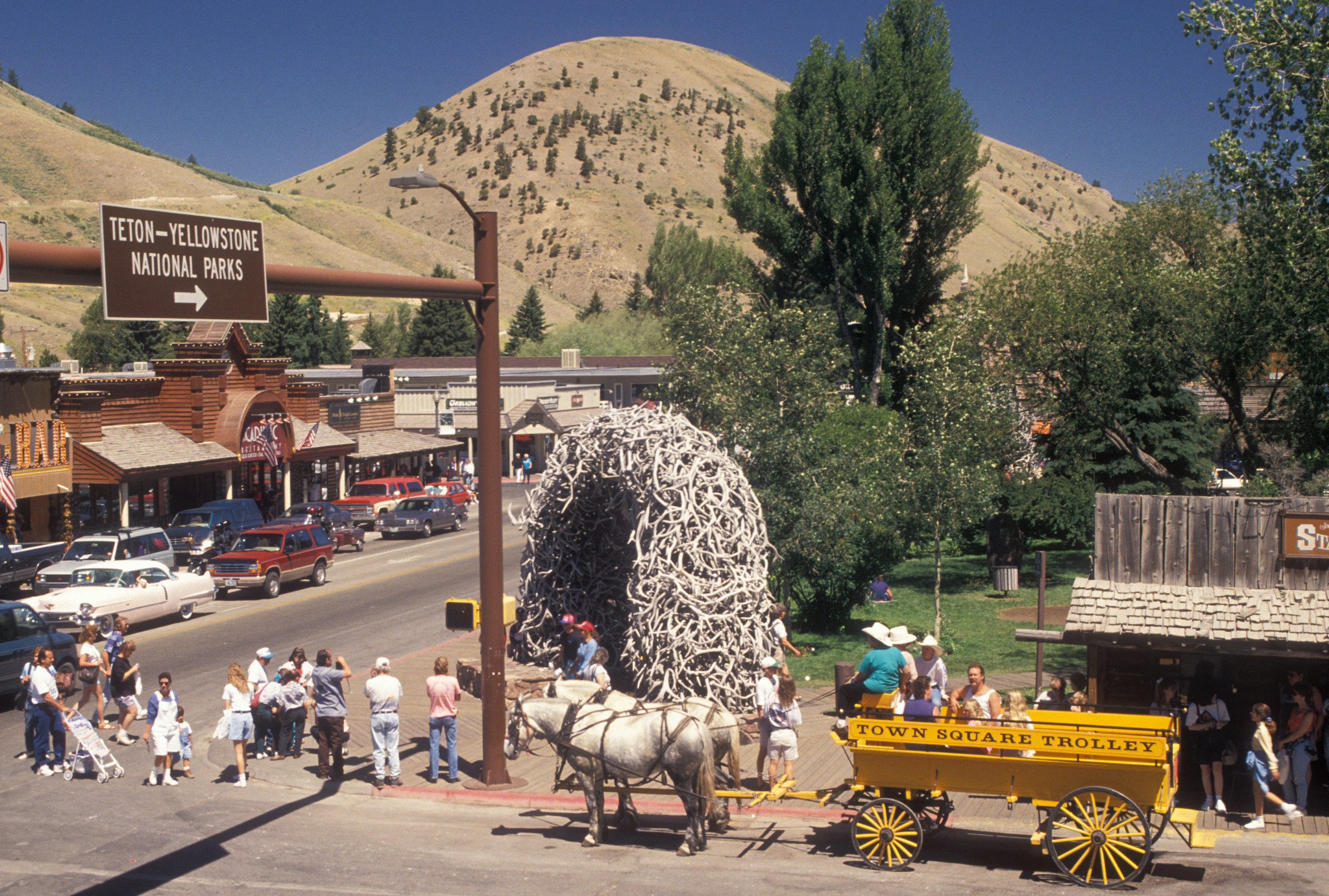 people walk along the sidewalk as a trolley pulls a group in Jackson Hole, Wyoming