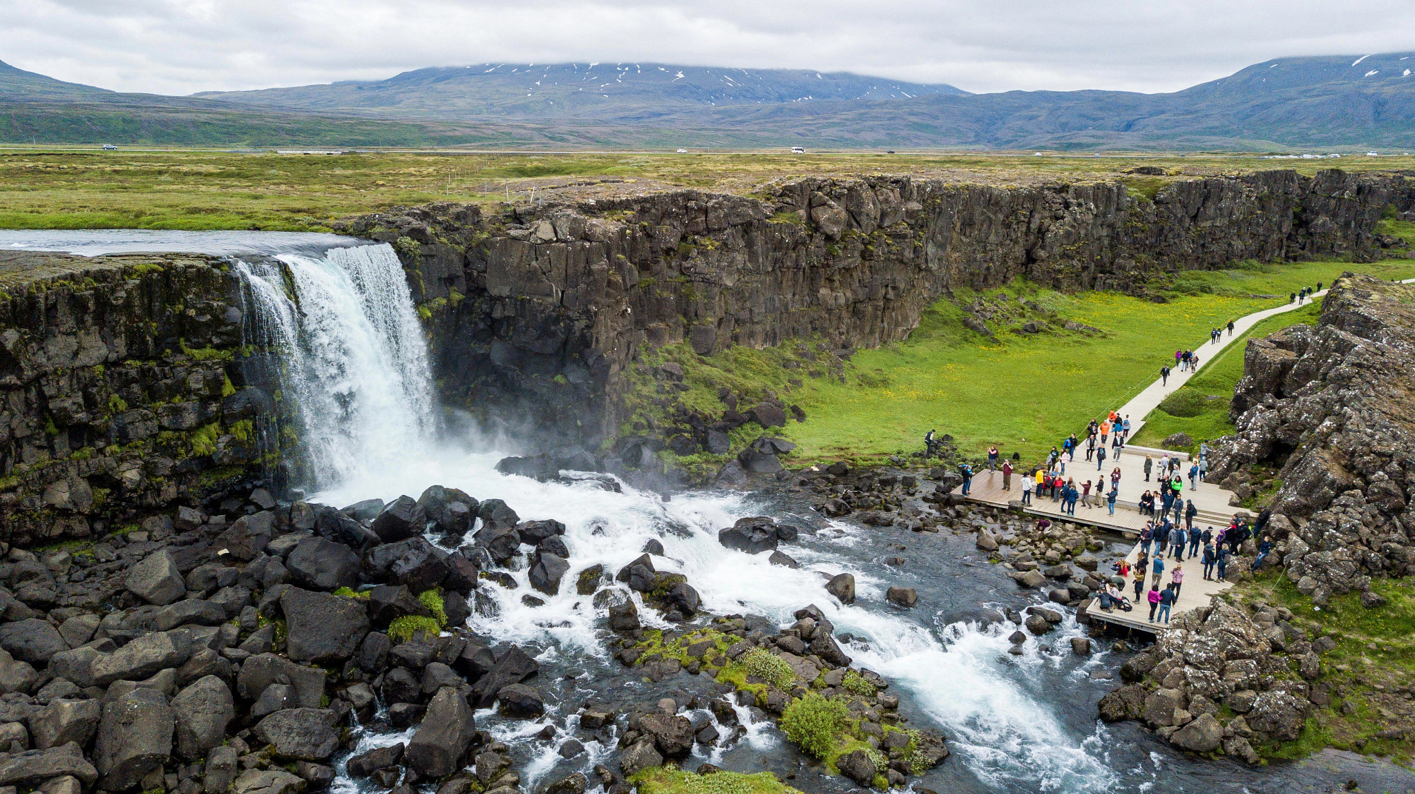 Overhead view of waterfalls at Thingvellir National Park with a viewing platform full of tourists