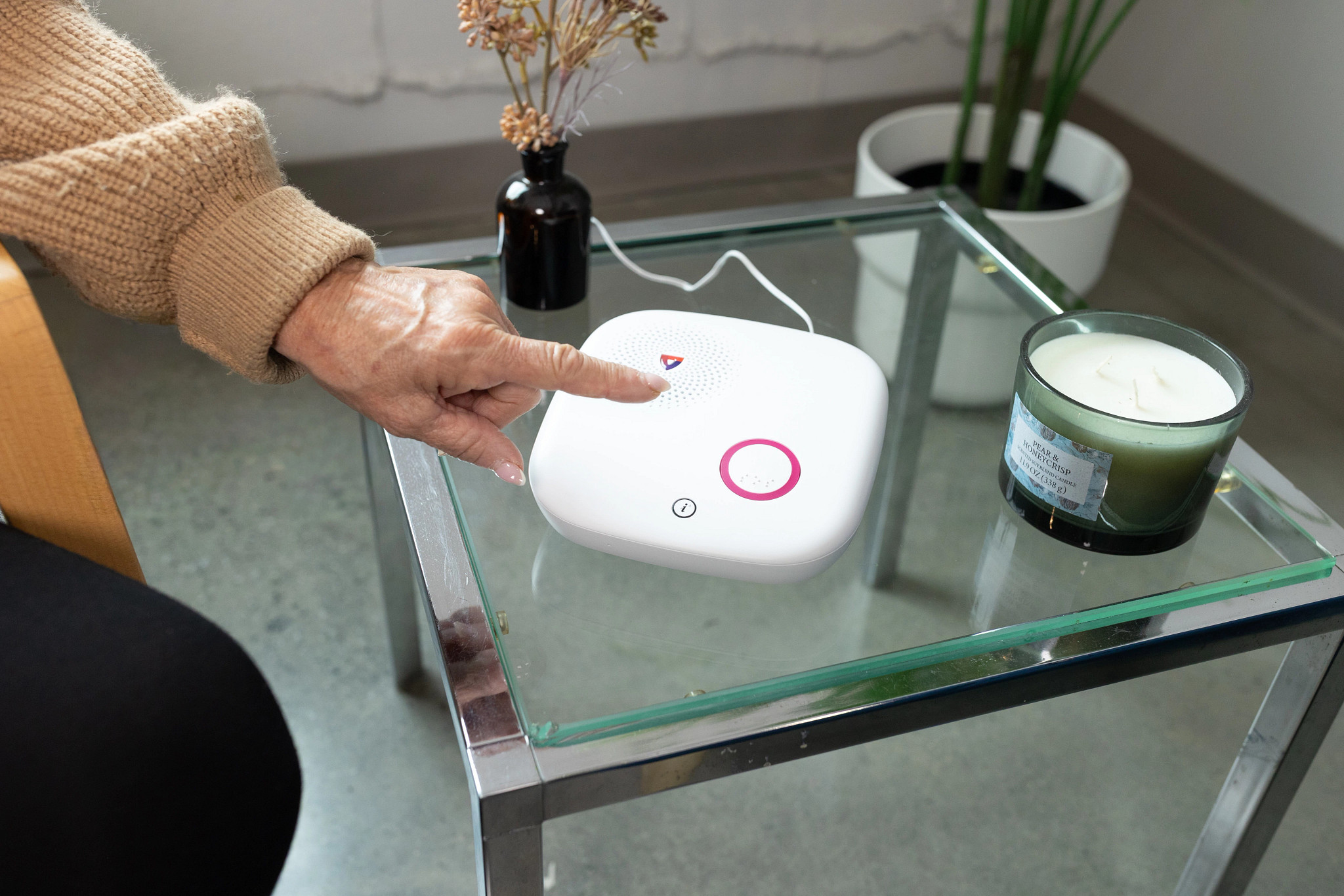 A woman points to the base unit of the Medical Guardian Home 2.0 device