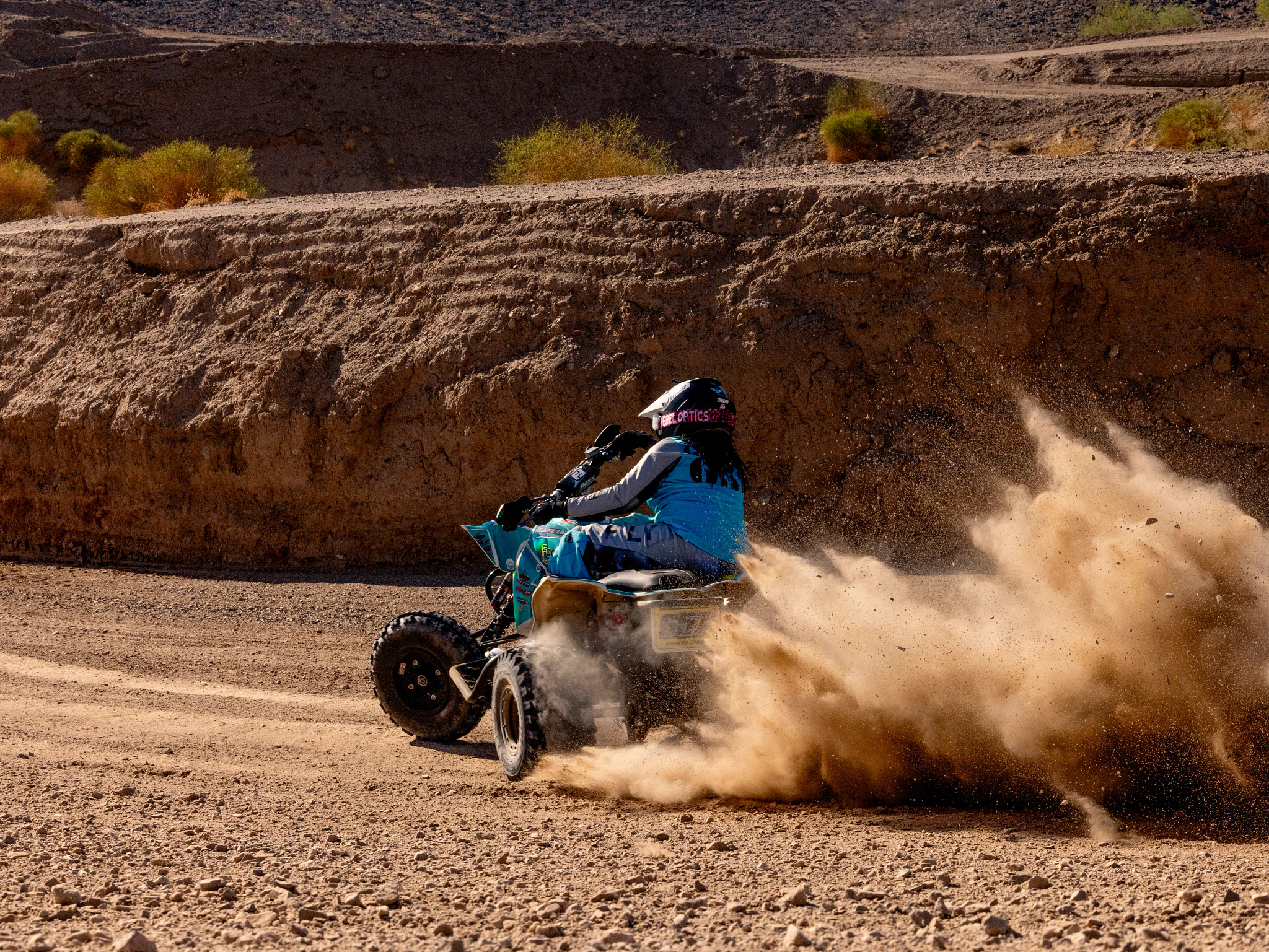 A photo shows ATV racer Marsha Garcia spinning up dirt with her competition four-wheeler