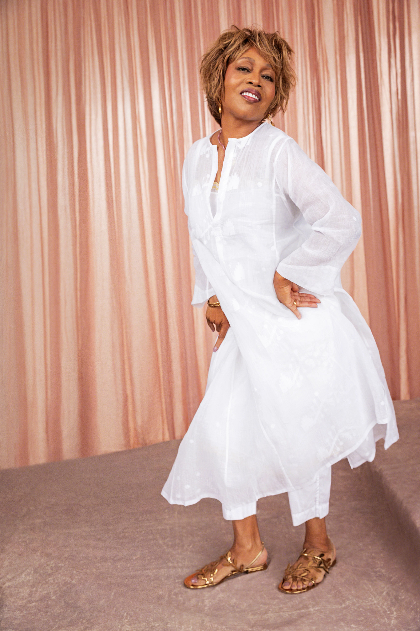 alfre woodard striking a joyful pose, wearing a white tunic