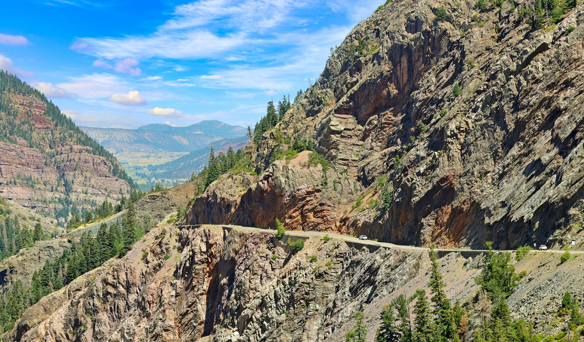 cars driving along a road on a mountainside 