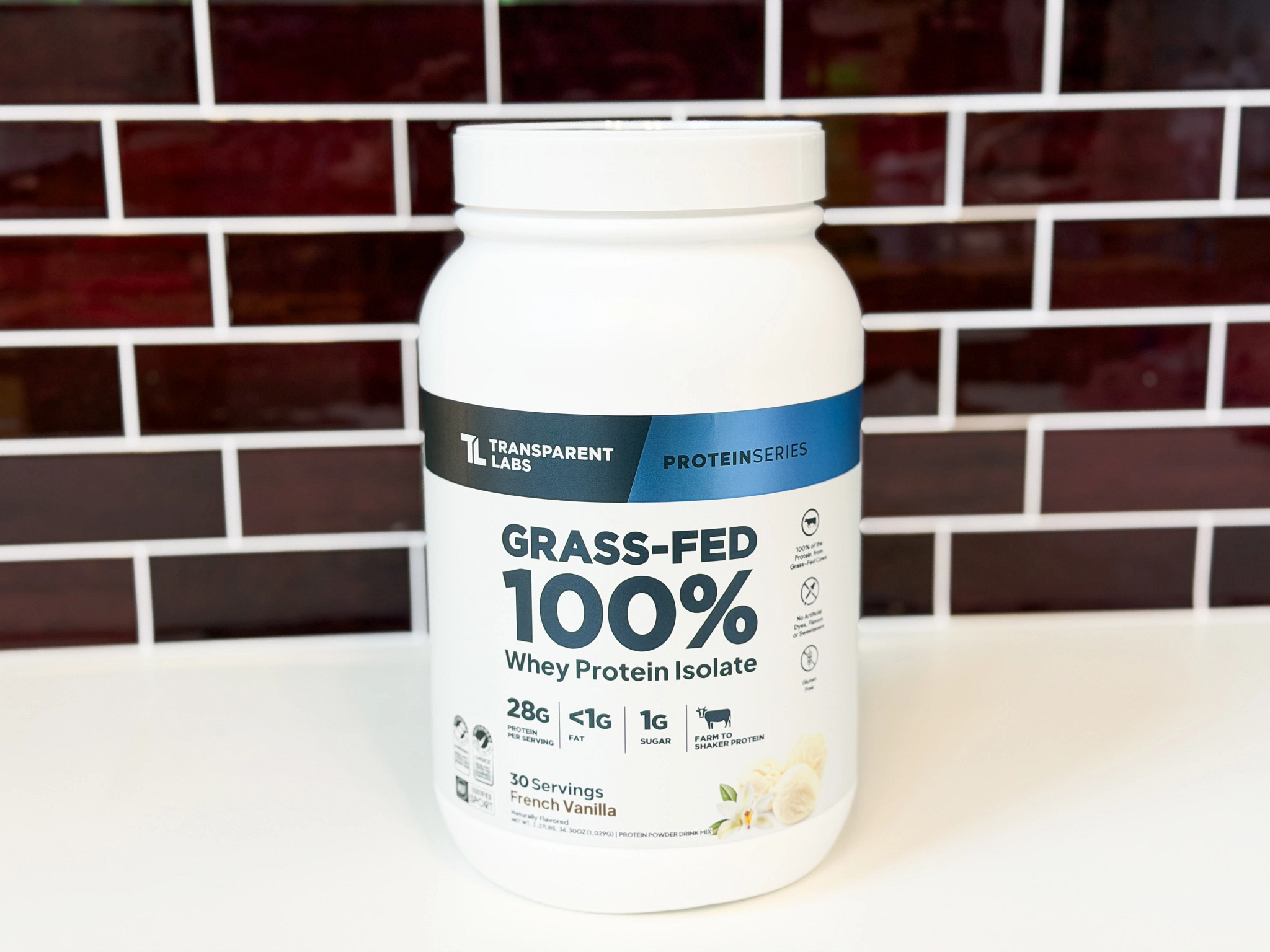 A container of Transparent Labs Grass-Fed Whey Protein Isolate with a brick background