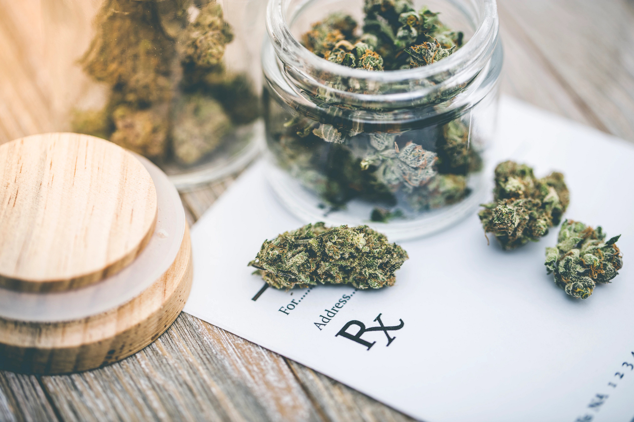 Medical marijuana cannabis buds in glass jars resting on a prescription form, illustrating questions about Medicare coverage and CBD or marijuana-based treatments for older adults.