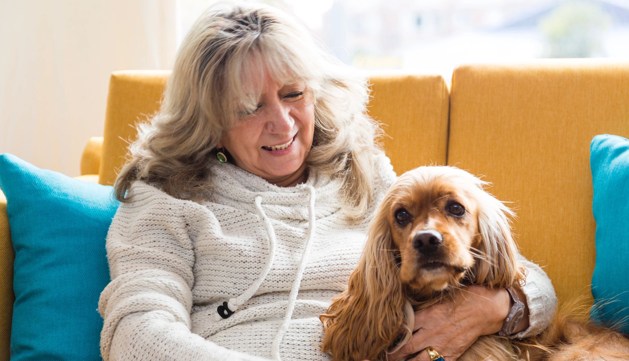a woman cuddling with a Cocker spaniel on a couch