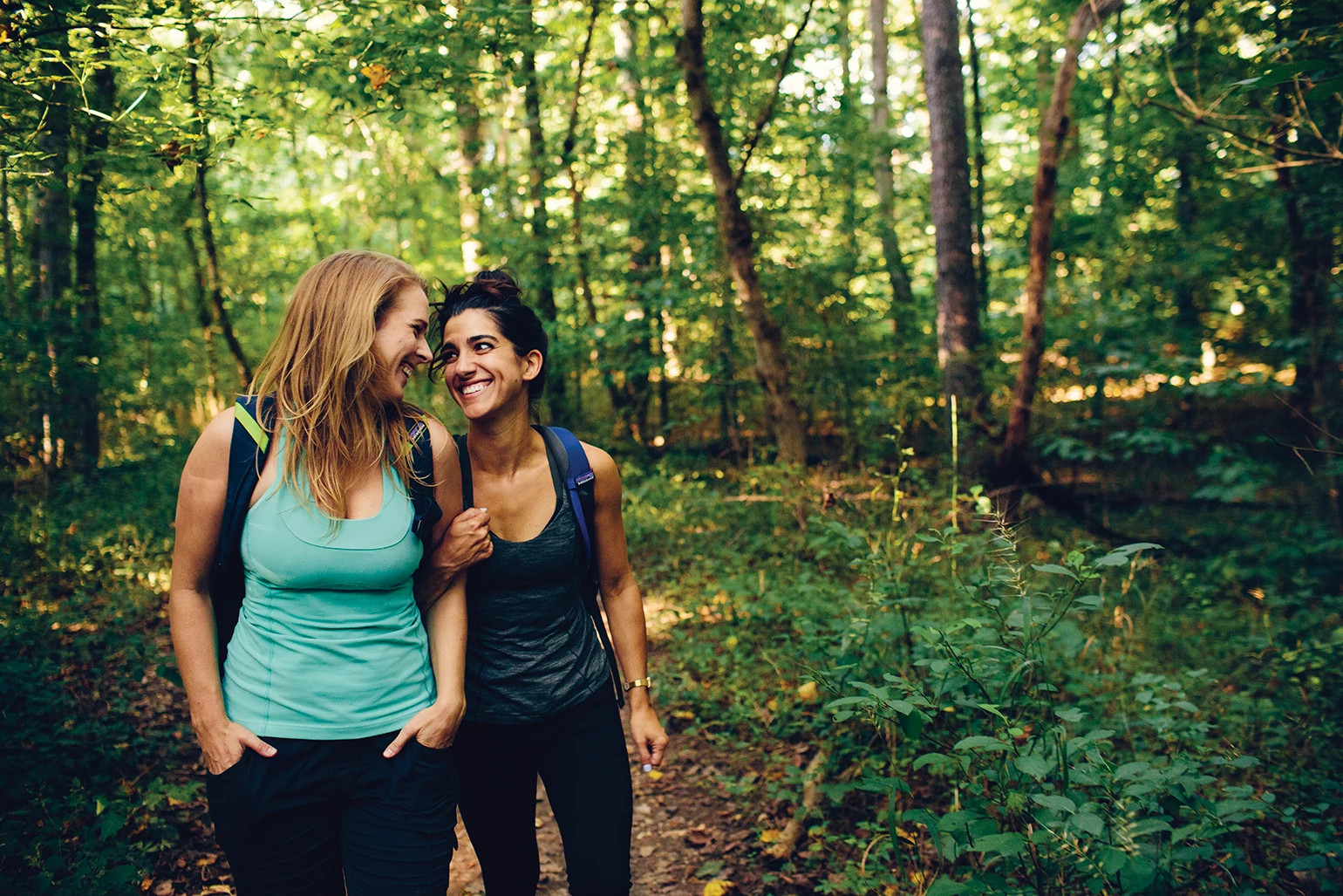 Two women best friends on a hike in the woods.