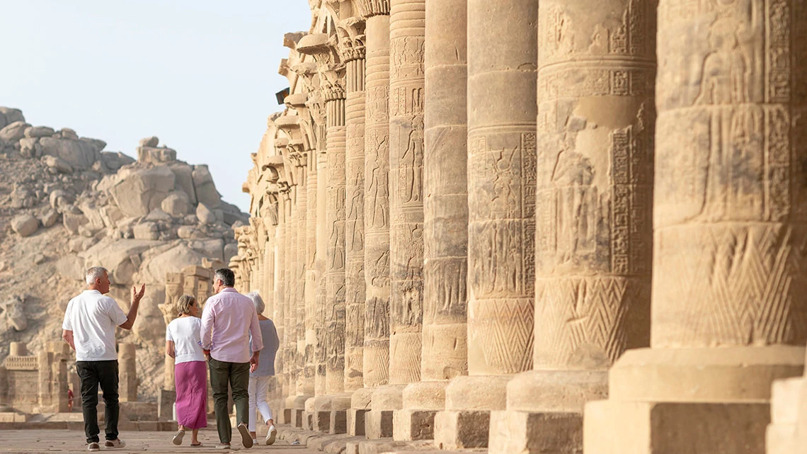 Grand European Travel: Rail & Tours two men and two women walking outside next to ancient pillars, sand and rock terrain