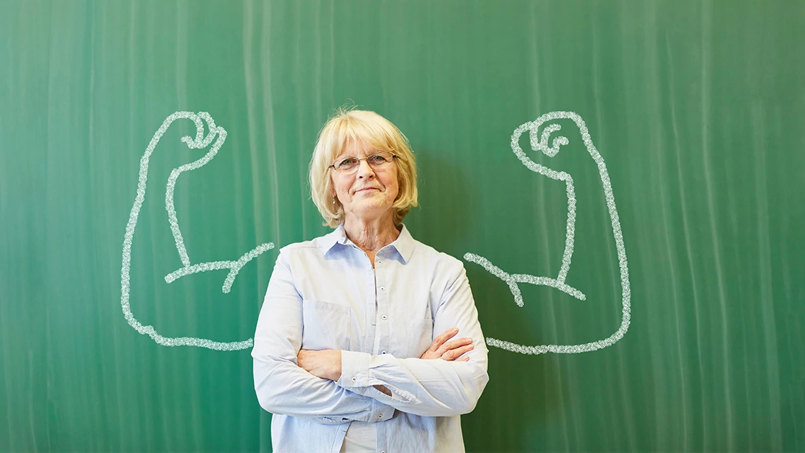 AARP Foundation Experience Corps Strong senior teacher with chalk muscles in front of chalkboard