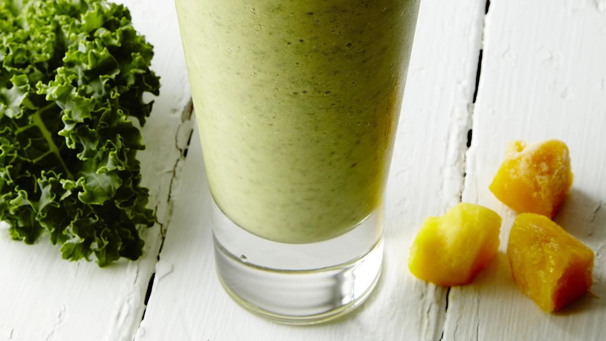 A close-up view of mango-coconut green smoothie in a glass