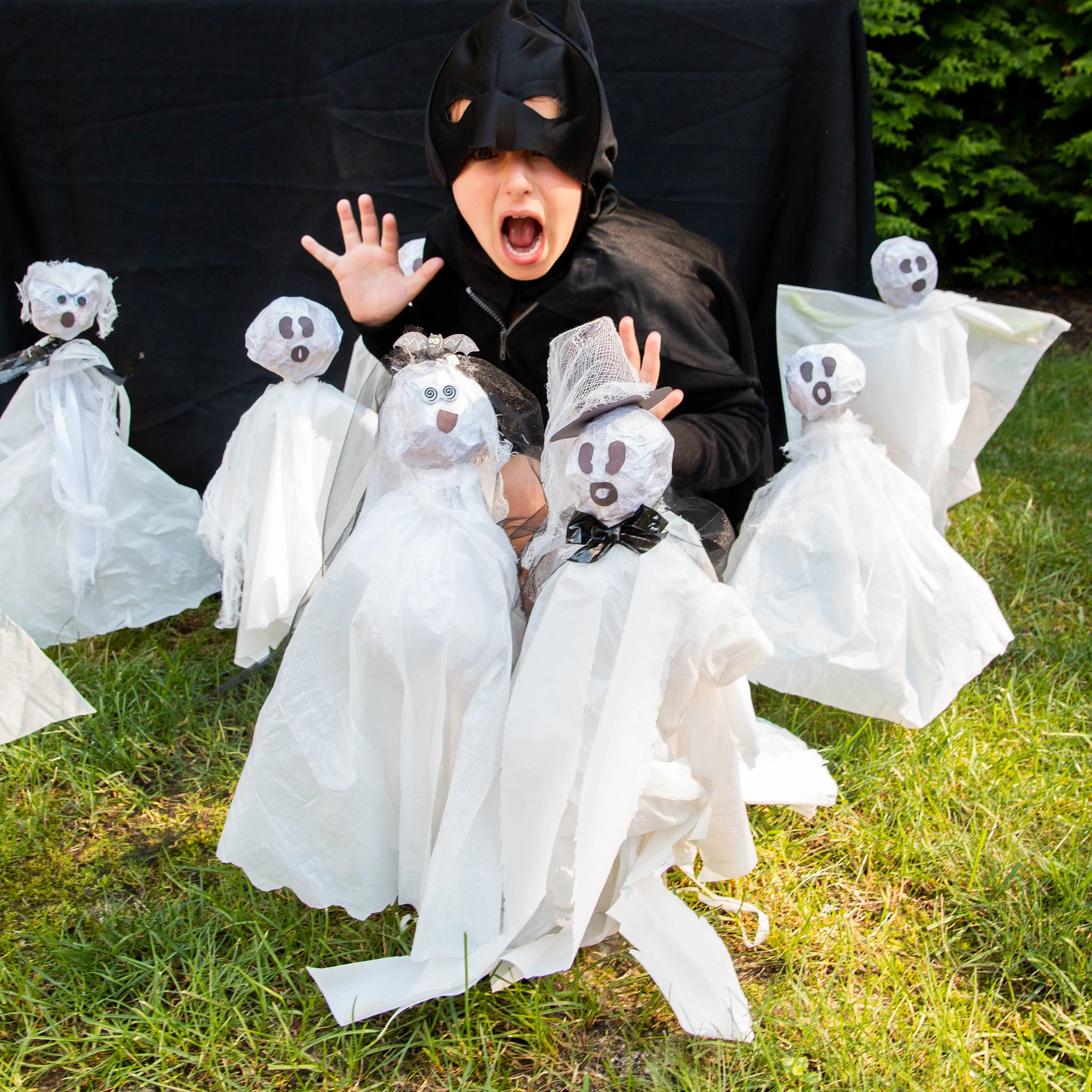 A child in a black Halloween costume with a collection of gauzy ghosts