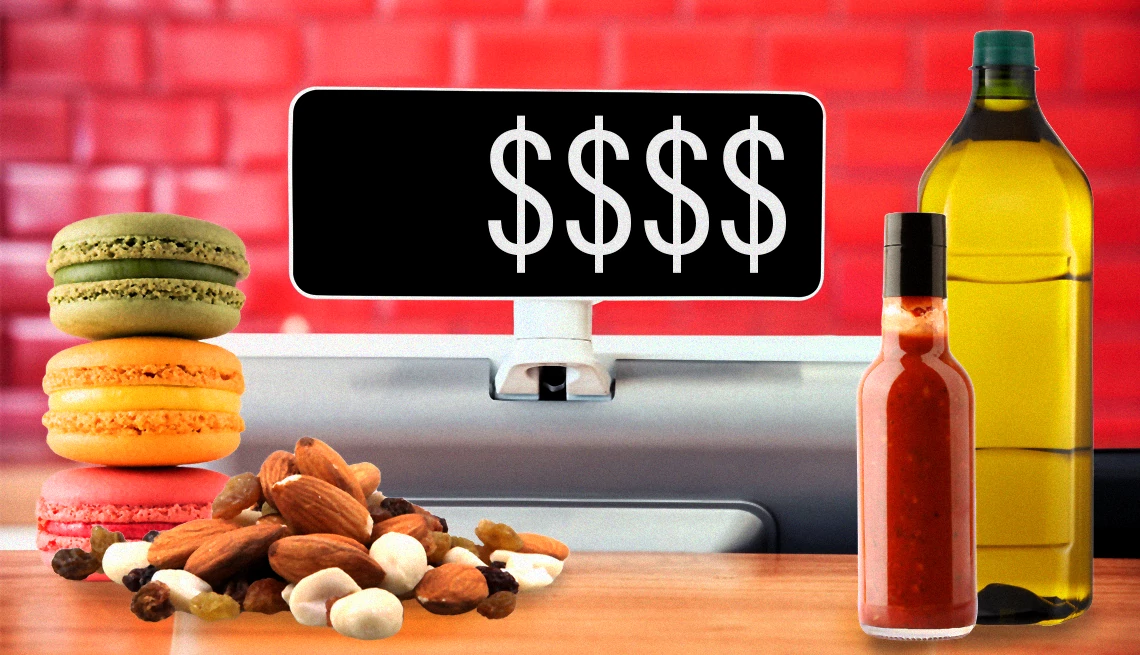 What to Splurge on at the Supermarket a register with dollar signs behind macarons, nut mix, hot sauce and olive oil
