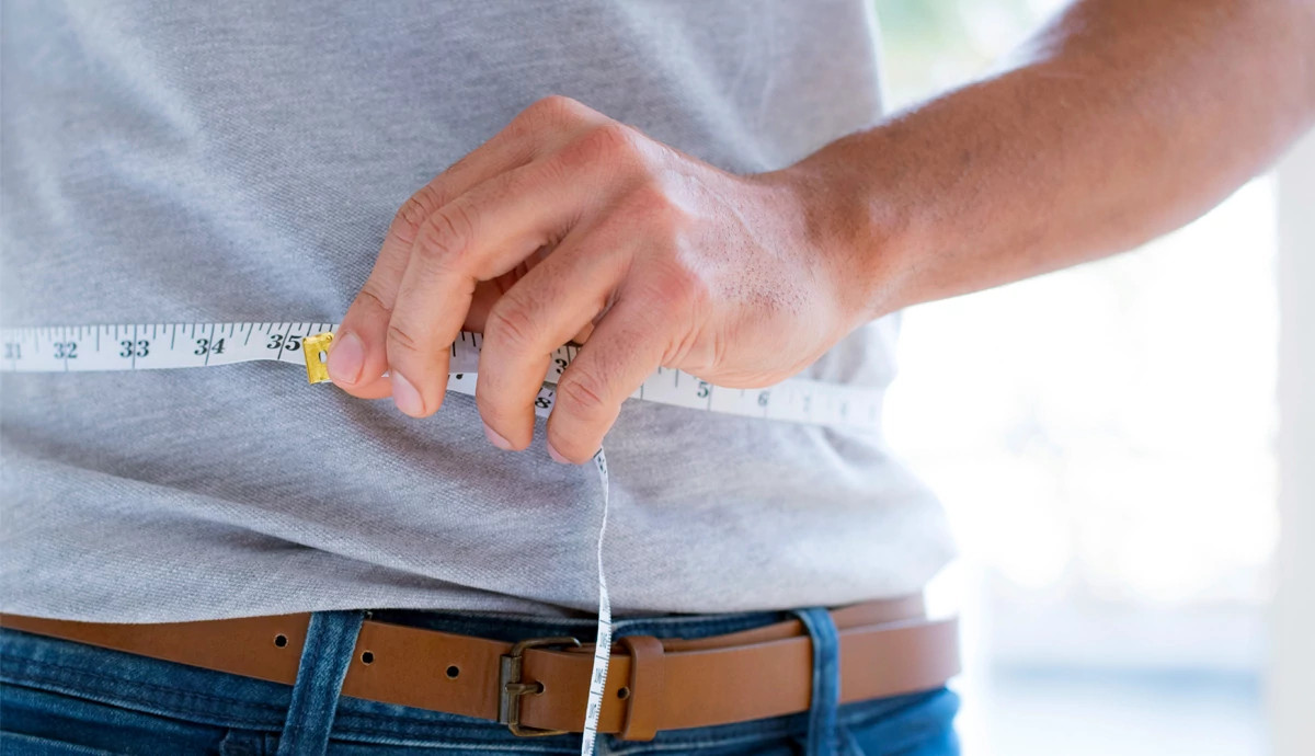 Close-up of a person measuring their waist with a tape measure
