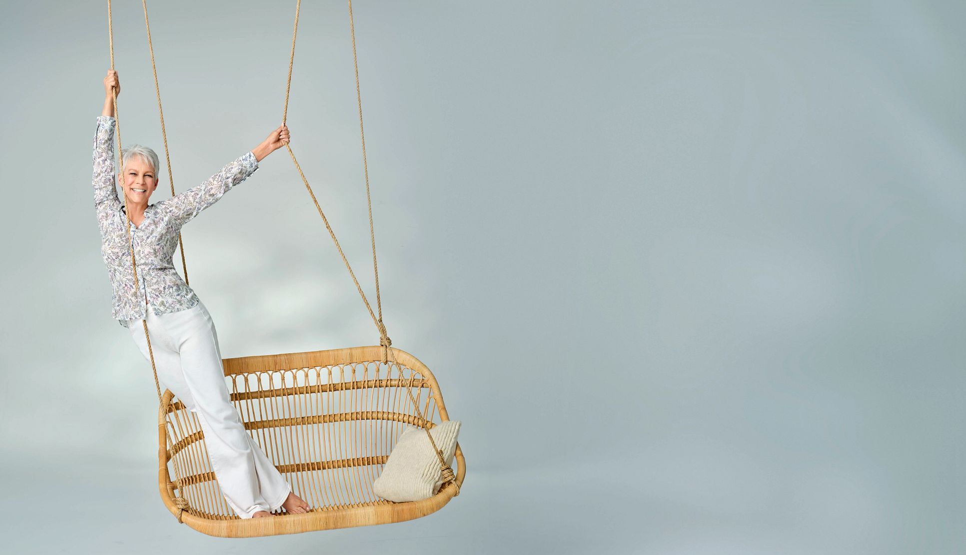 The Liberation of Jamie Lee Curtis jamie lee curtis smiling while standing on a hanging wicker swing, holding onto the ropes