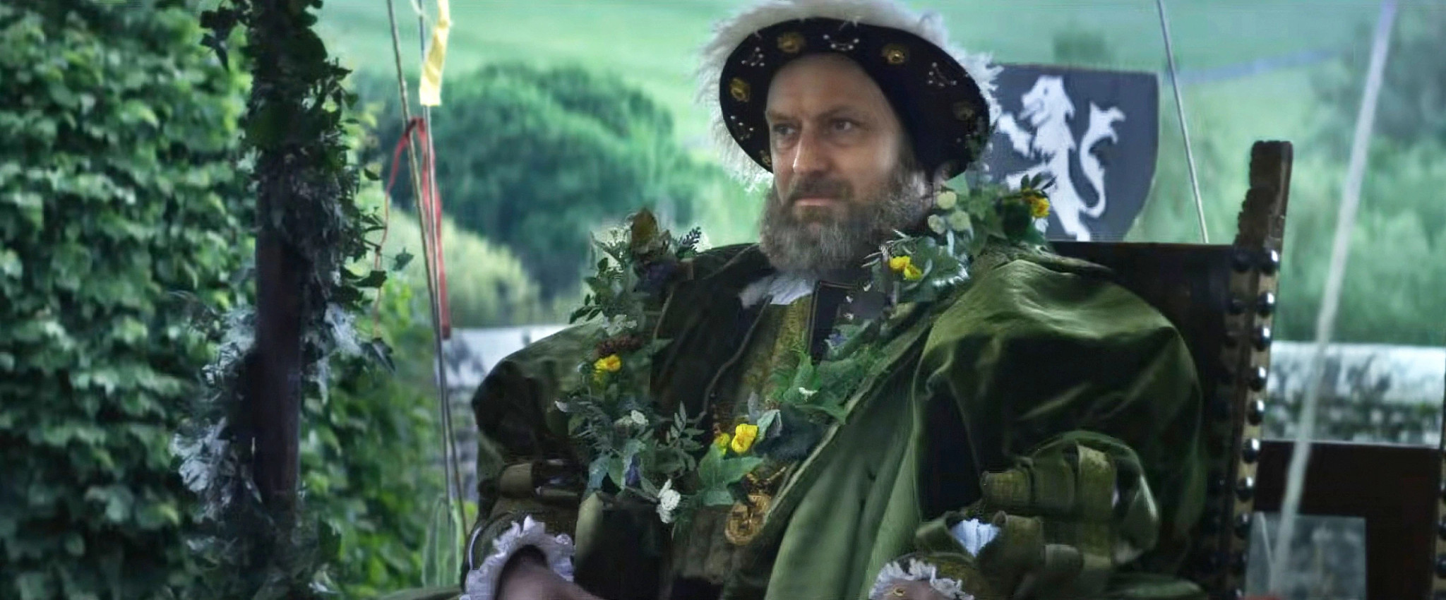 Jude Law sitting in a chair as Henry VIII in the film Firebrand