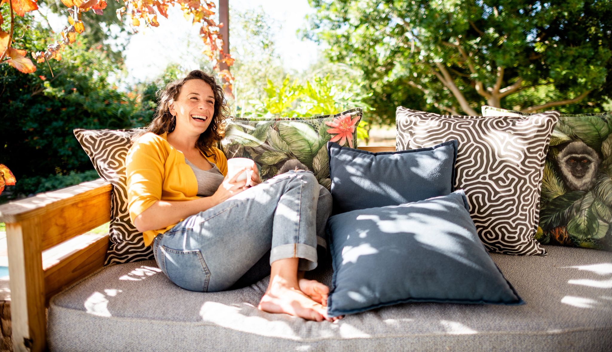 Dementia caregivers who neglect self-care can jeopardize their own health and well-being A woman relaxing outside on her patio sofa with a cup of coffee in her hands